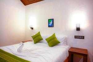 una camera da letto con un letto bianco con cuscini verdi di Coorg Mystere - Luxury Homestay a Madikeri