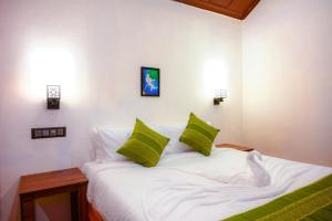 una camera da letto con un letto bianco con cuscini verdi di Coorg Mystere - Luxury Homestay a Madikeri