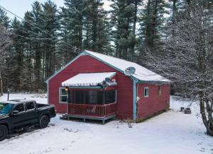 une maison rouge avec un camion garé dans la neige dans l'établissement Modern & Cozy Getaway House near Conway lake - Pet Friendly, à Conway