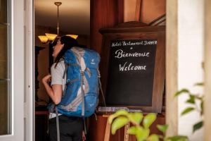 uma pessoa com uma mochila à porta em Logis Hotel-Restaurant Dimmer em Wallendorf pont