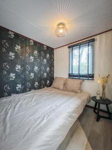 a bedroom with a large white bed and a window at Chalet op familiepark Veluws Hof op de Hoge Veluwe in Hoenderloo