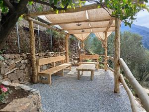 a wooden pergola with a bench and a swing at Ελαιώνας - Solar Energy House in Chorefto