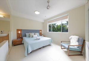 ein Schlafzimmer mit einem Bett, einem Stuhl und einem Fenster in der Unterkunft Whitsundays Ocean & Rainforest views Airlie Beach in Airlie Beach