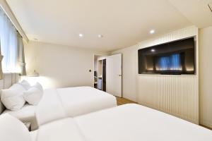 a hotel room with two beds and a flat screen tv at Denbasta Hotel Daeyeon in Busan