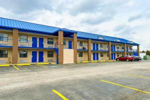 um grande edifício com janelas azuis e um parque de estacionamento em Happy Stay Inn Madisonville I-69 By OYO em Madisonville