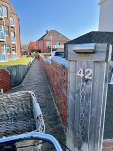 un panneau sur le côté d'un mur de briques avec un banc dans l'établissement Haus Dollart, à Borkum