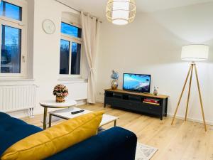 un salon avec un canapé bleu et une télévision dans l'établissement Twenty Five Apartment bei Dresden - free Parking - Massagestuhl - Netflix - Coffee Machine, à Heidenau