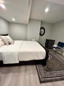 ein Schlafzimmer mit einem großen weißen Bett und einem Stuhl in der Unterkunft APARTMENT B 2 BEDROOM in Brampton