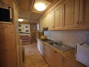 a kitchen with wooden cabinets and a sink at Appartamento Brentegani in Arabba