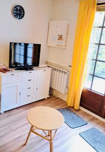 sala de estar con TV, taburete y mesa en Maisonnette du bonheur, en Courseulles-sur-Mer