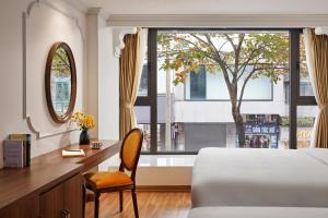 a bedroom with a bed and a desk and a window at Eliana Premio Hotel Hanoi in Hanoi