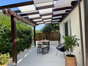 un patio con mesa y sillas bajo una pérgola de madera en Studio D2, en Biograd na Moru