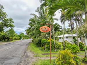 un cartello stradale sul lato di una strada con palme di Bella Beach Bungalows a Rarotonga