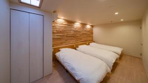 two beds in a room with a wooden wall at UTAKATA HOTEL HIMEJI in Himeji