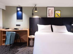 Habitación de hotel con cama y escritorio en ibis Paris Grands Boulevards Opéra 9e, en París