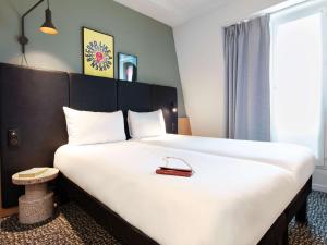 un dormitorio con una gran cama blanca con un bolso en ibis Paris Grands Boulevards Opéra 9e, en París