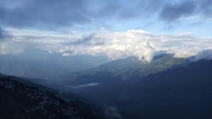 uma vista para uma montanha com nuvens no céu em Sunrise Homestay em Darjeeling