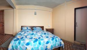 um quarto com uma cama azul e branca com almofadas azuis em Sunrise Homestay em Darjeeling