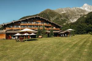 um grande edifício com um campo de relva em frente em Les Grands Montets Hotel & Spa em Chamonix-Mont-Blanc