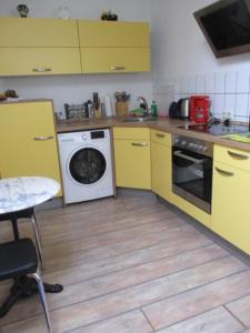 eine Küche mit gelben Schränken und einer Waschmaschine in der Unterkunft Ferienwohnung Thüringer Wald in Ilmenau