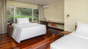 a bedroom with two beds and a desk and a window at Fairview Hotel Nairobi in Nairobi