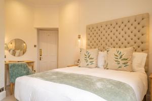 a bedroom with a large white bed with a large headboard at Lindeth Fell Country House in Bowness-on-Windermere