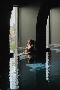 una mujer sentada en un alféizar en el agua en NINE DOTS Azorean Art Boutique Hotel, en Ponta Delgada