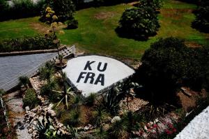 a sign that says ku frfa in a garden at Hotel Oasi Di Kufra in Sabaudia