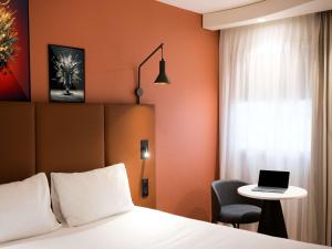 een hotelkamer met een bed en een laptop op een tafel bij IBIS Port de plaisance in Caen