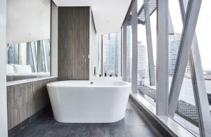 eine weiße Badewanne im Bad mit Fenstern in der Unterkunft Alila SCBD Jakarta in Jakarta