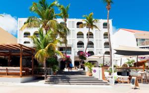 un grande edificio bianco con palme di fronte di Holland House Beach Hotel a Philipsburg