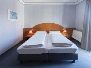 twee bedden in een hotelkamer met twee lampen bij B&B HOTEL Gotha-Hbf in Gotha