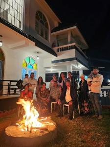 Un groupe de personnes assises autour d'un feu devant une maison dans l'établissement Hestia Chalet 3BHK Villa, à Ooty