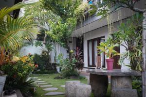 un jardín con una mesa de piedra frente a un edificio en Bali Full Moon Guest House, en Canggu