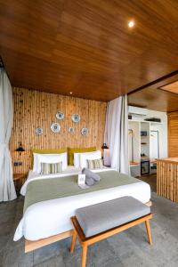 - une chambre avec un grand lit blanc et des murs en bois dans l'établissement The Elementum, à Uluwatu