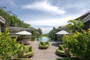 un patio avec des chaises vertes et une piscine dans l'établissement The Elementum, à Uluwatu