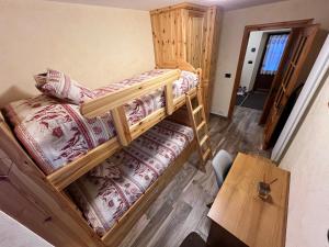 two bunk beds in a room with a table at Chalet Chez Louis - Alpine Charm with Mont Blanc View & Ski Access in Courmayeur