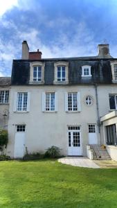 una grande casa bianca con porte bianche e un prato di Le Hêtre Pourpre a Bayeux