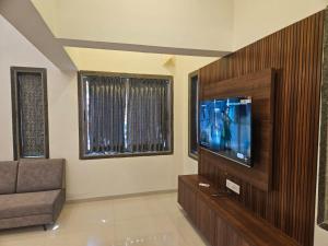 een woonkamer met een bank en een flatscreen-tv bij Seven Villa with Swimming pool in Panchgani