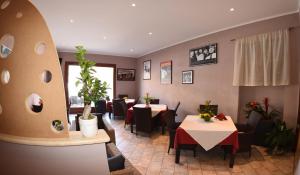 a restaurant with two tables and chairs and plants at Albergo La Perla in Orbetello