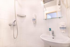 baño blanco con ducha y lavamanos en ARIBĖ Hotel Klaipėda, Free parking, en Klaipėda