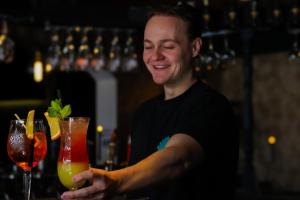 Ein Mann steht an einer Bar und hält zwei Cocktails. in der Unterkunft Hotel Grand Cafe Deight in Zandvoort