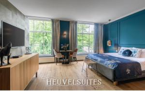 Schlafzimmer mit blauen Wänden, einem Bett und einem Tisch in der Unterkunft Heuvelsuites in Oosterhout