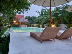 een zwembad met 2 stoelen en een parasol bij Uluwatu Desa in Uluwatu