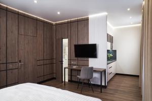 1 dormitorio con 1 cama y escritorio con TV en BonApart Maidan by UHM, en Kiev