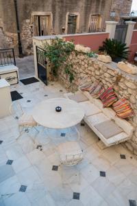 une table et des chaises sur une terrasse avec un mur en pierre dans l'établissement Silo Luxury Rooms, à Nauplie