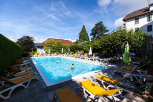 a large swimming pool with chairs and people in it at Hotel du Lac in Talloires