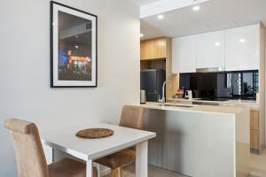 - une cuisine blanche avec une table et des chaises blanches dans l'établissement Cosy 1-Bed with River Views Pool Gym & BBQ, à Brisbane