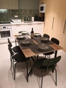 a wooden table with black chairs and a bottle of wine at Apartamento céntrico Sitges, cerca de todo andando in Sitges