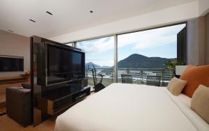 una camera da letto con un grande televisore e una grande finestra di Nina Hotel Island South a Hong Kong